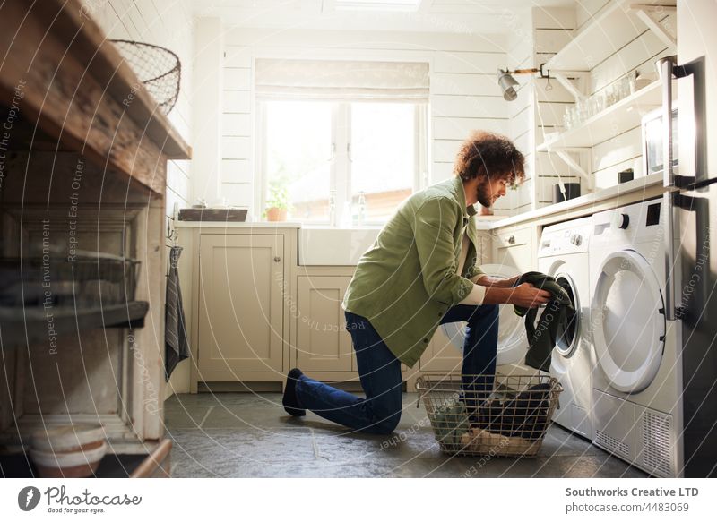 Mann belädt Waschmaschine in Küche gemischte Rasse eine Erwachsener im Innenbereich Lifestyle Hausarbeiten Tag heimwärts allein authentisch Wäschetrockner Raum