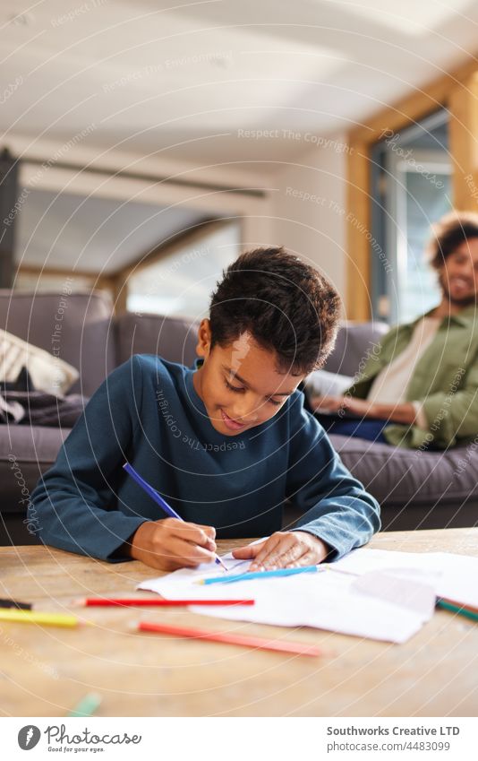 Junge zeichnet auf Papier auf Couchtisch zu Hause gemischte Rasse Kind zeichnen Kunst Kreativität Konzentration lernen im Innenbereich Tag heimwärts zwei