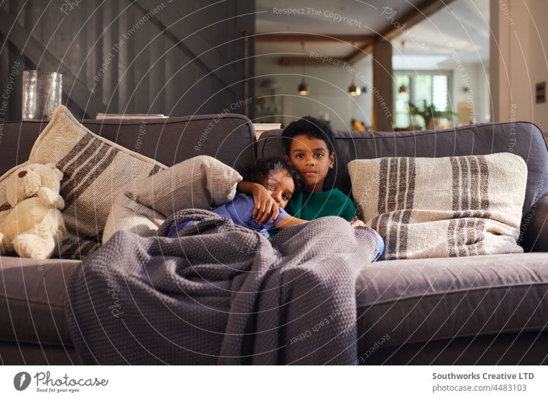 Zwei Jungen kuscheln auf dem Sofa unter einer Decke gemischte Rasse zwei Kind Bruder Pflege Liebe Zusammensein im Innenbereich Tag heimwärts Menschen Porträt