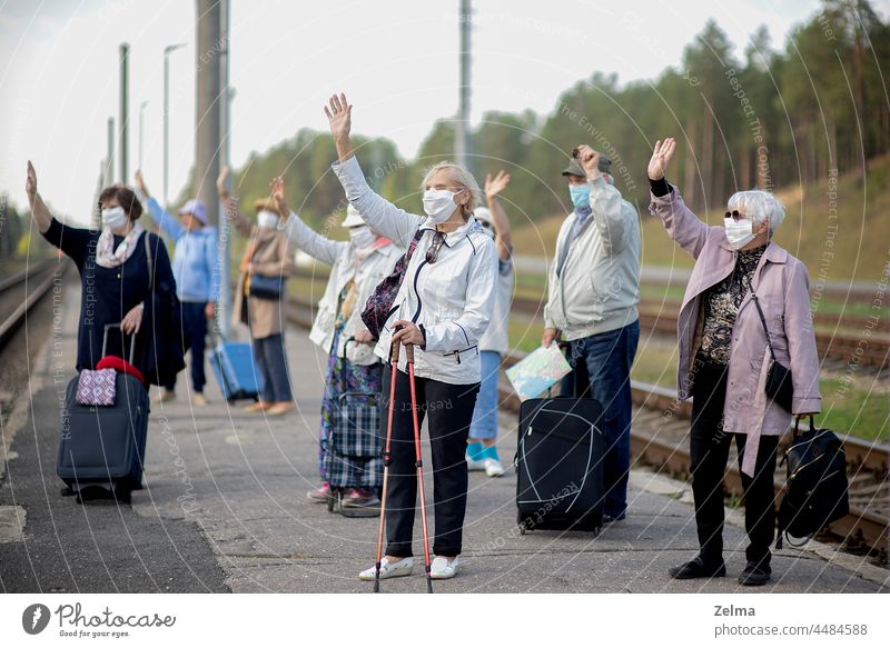Gruppe älterer Menschen mit Gesichtsmasken, die auf den Zug warten, bevor sie während einer Pandemie reisen Senior Menschengruppe alt medizinisch Mundschutz