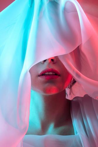 Studio-Porträt einer Frau mit neonblauen und roten Blitzen in den Augen bedeckt Stoff neonfarbig Model künstlerisch dunkel allein Hipster cool stylisch retro