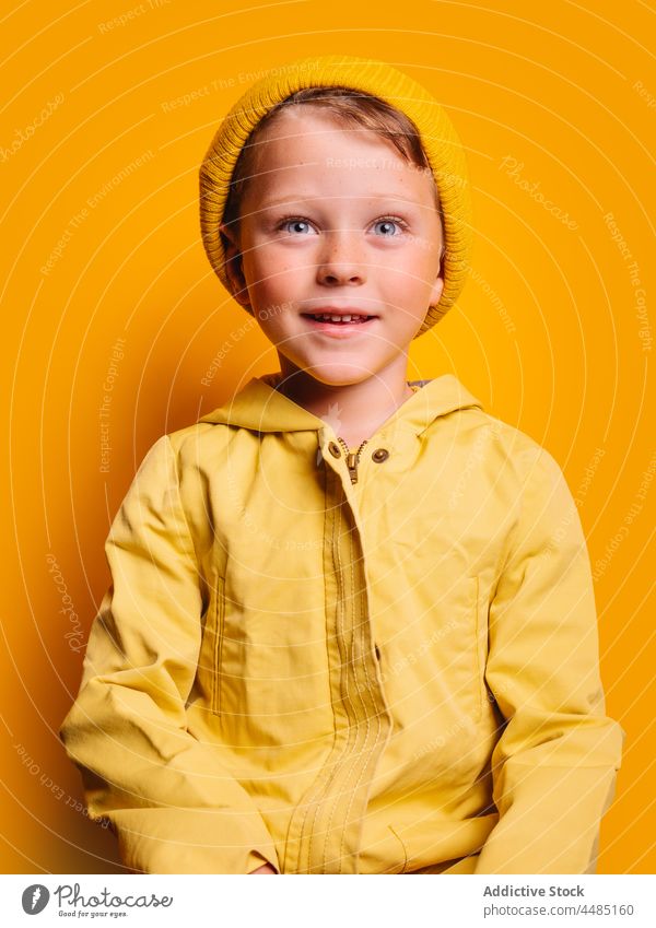 Lachender Junge schaut in die Kamera vor gelbem Hintergrund Glück heiter Herbst Porträt Jacke Oberbekleidung Beanie froh Freude Stil Kind trendy hell Outfit
