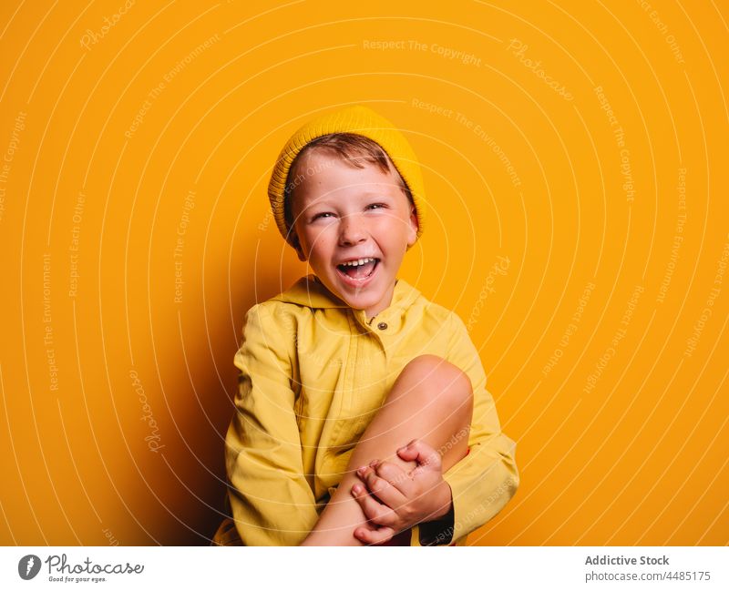 Lachender Junge schaut in die Kamera vor gelbem Hintergrund Glück heiter Herbst Porträt Jacke Oberbekleidung Beanie froh Freude Stil Kind trendy hell Outfit