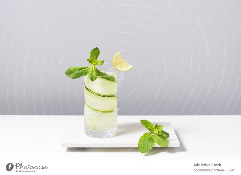 Erfrischender Cocktail mit Limette und Gurke, serviert auf einem weißen Tisch Gin Tonic Kalk Salatgurke Zitrusfrüchte Alkohol Minze Getränk Frucht cool