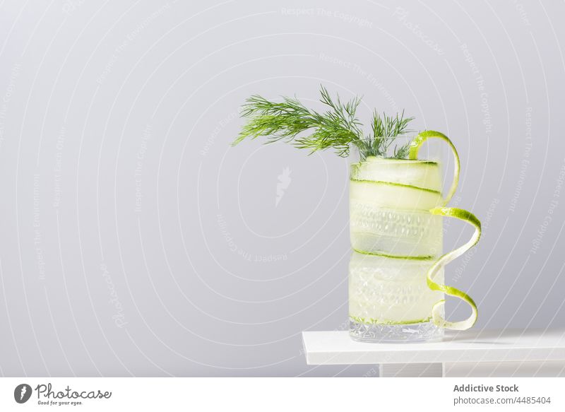Glas mit kaltem Cocktail, dekoriert mit Limettenschale und Fenchel Gin Tonic Kalk Alkohol Getränk Erfrischung Salatgurke Zitrusfrüchte Schale Schnaps Eis dienen