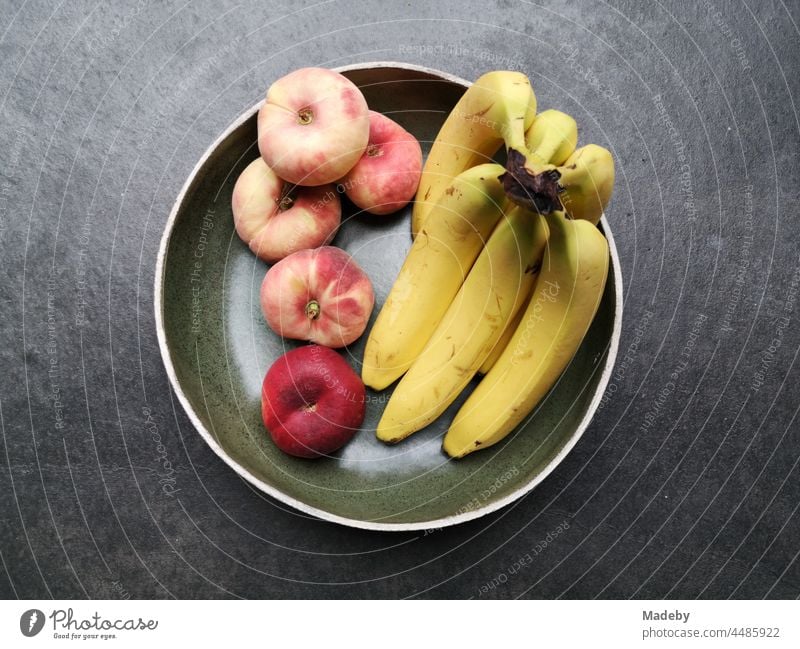 Runde Schale aus Keramik mit Banane, Pfirsich und Apfel auf grauem Betonboden in einer Designerwohnung tun Rudersau bei Rottenbuch im Kreis Weilheim-Schongau in Oberbayern