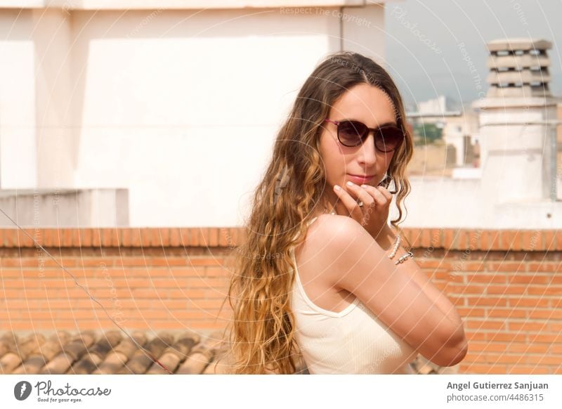 Junge Frau mit Sonnenbrille posiert an einem sonnigen Tag im Freien. jung Brille posierend Stil Sommer lässig eine Person urban Fotografie junger Erwachsener