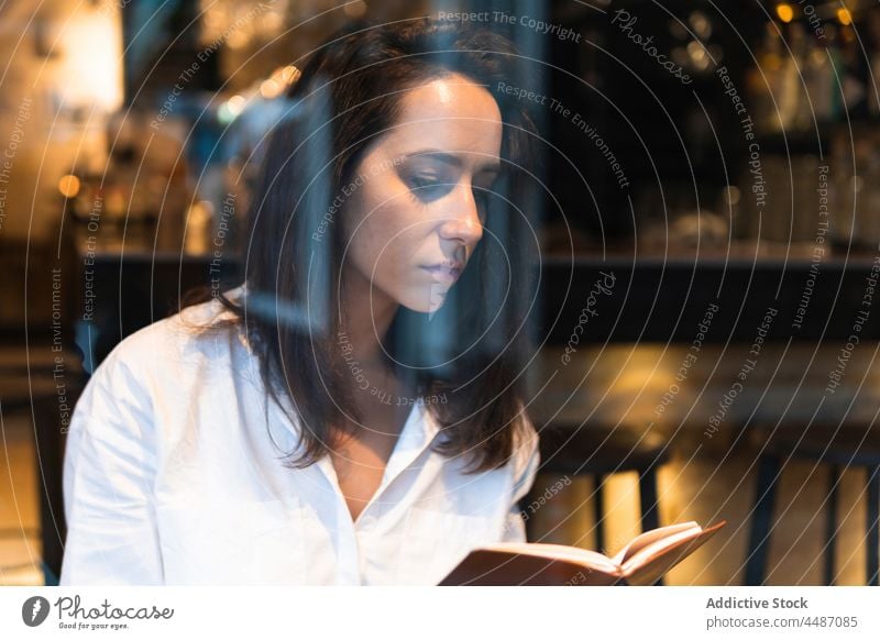 Nachdenkliche Frau, die in einem Café ein Buch liest Konzentration Wissen Hobby lernen Fokus ernst Bildung lesen jung Literatur nachdenklich besinnlich