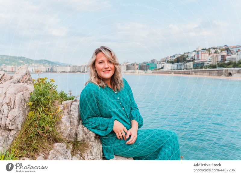 Verträumte Frau sitzt auf Felsen mit grünen Pflanzen in der Nähe des Meeres Stil Natur positiv verträumt ausrichten MEER Umwelt donostia trendy San Sebastián