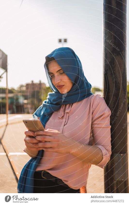 Glückliche muslimische Frau mit Smartphone auf der Straße benutzend Nachricht Hijab Kopftuch Lächeln heiter Surfen Großstadt ethnisch arabisch Telefon Browsen