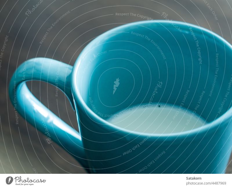 Milch in einer blauen Tasse auf dem Holztisch mit Glasplatte melken braun weiß Licht heiß hölzern Top Tisch Frühstück Stock Hintergrund Farbe altehrwürdig