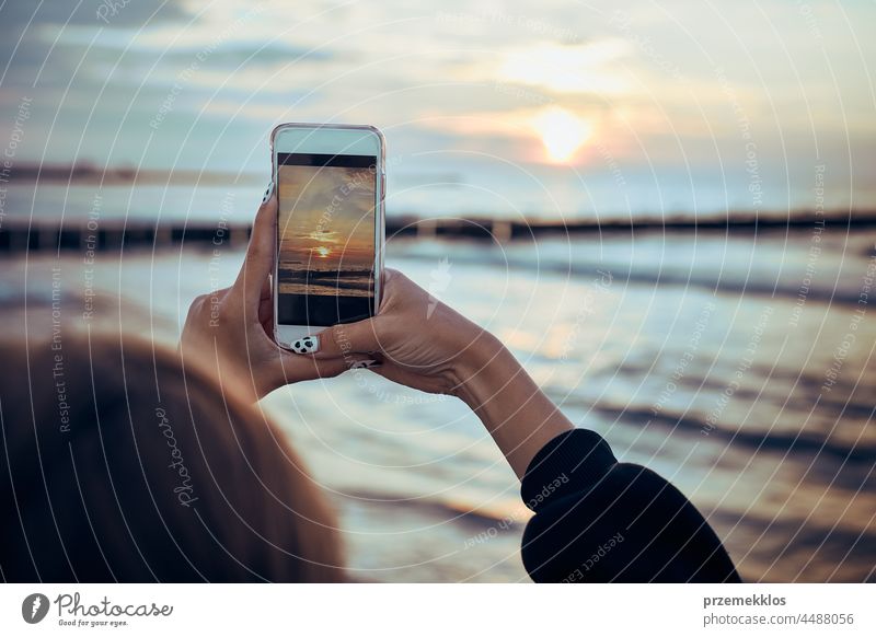 Junge Frau fotografiert den Sonnenuntergang über dem Meer mit ihrem Smartphone während einer Sommerreise Foto MEER Fotograf Bild Technik & Technologie