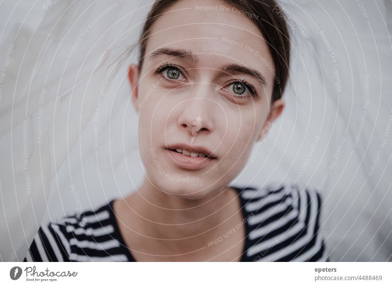 Junge attraktive Frau mit gestreiftem T-Shirt unter transparenter Plastikfolie schaut in die Kamera Erwachsener Hintergrund schön Schönheit brünett Kaukasier