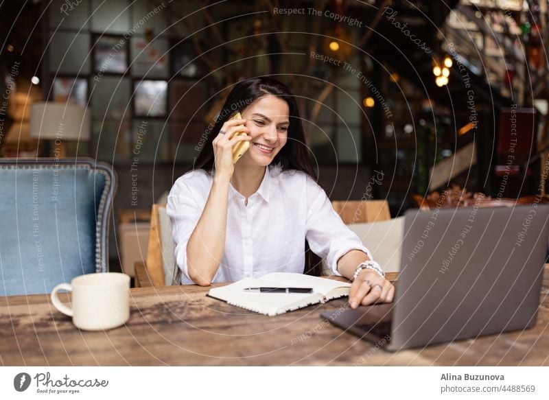 Junge kaukasische Geschäftsfrau mit langen brünetten Haaren arbeitet an einem Laptop in einem Café. College-Student mit Technologie Frau Business online Telefon