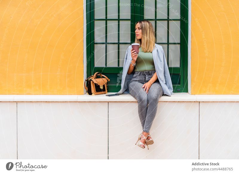 Stilvolle Frau mit Kaffee zum Mitnehmen sitzt in der Nähe eines Gebäudes Imbissbude trinken Straße Großstadt Getränk Koffein trendy Pappbecher heiter positiv