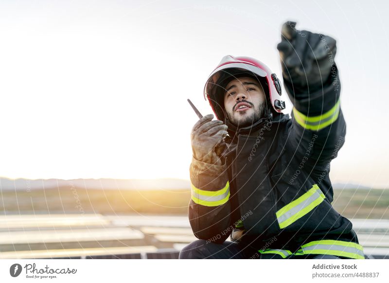 Junger Feuerwehrmann spricht in einen Sender Mann Schutzhelm sprechen Uniform Bericht Walkie-Talkie professionell Beruf Job Karriere Handschuh positiv männlich