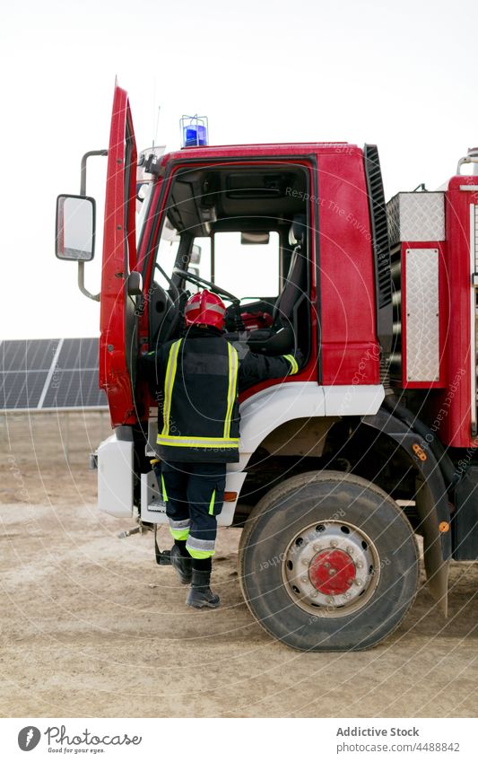 Feuerwehrmann steigt ins Feuerwehrauto ein Lastwagen Arbeit Notfall Beruf Gerät retten extrem Schutzhelm Mitarbeiter Uniform behüten Sicherheit Mut Held Alarm