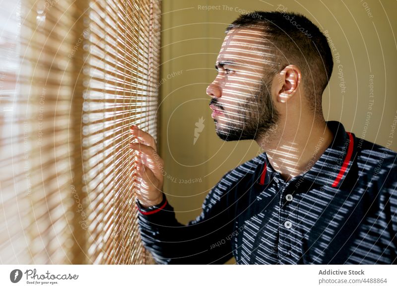 Mann schaut aus dem Fenster Feuerwehrmann Vollbart selbstbewusst Windstille Sweatjacke Station Beruf unrasiert jung sportlich männlich Sonnenlicht blind