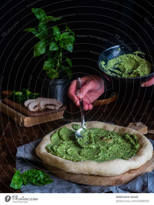 Kochen von Pizza mit Pestosauce Saucen hinzufügen vorbereiten grün lecker Basilikum Lebensmittel Küche geschmackvoll Küchenchef Feinschmecker italienische Küche