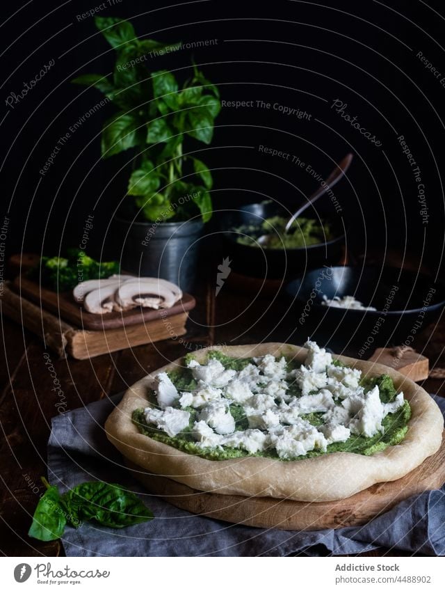 Ungekochte Pizza mit Pestosauce und Käse Saucen Vegetarier ungekocht ganz Tisch Italienische Küche Basilikum Mozzarella Lebensmittel Mahlzeit lecker grün