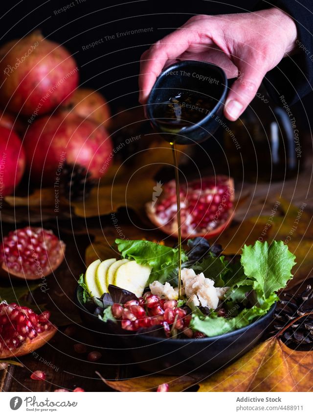 Gießen Sie das Olivenöl in eine Schüssel mit Granatapfelsalat Koch Salatbeilage eingießen hinzufügen Speise Vegetarier Küchenchef Flasche kulinarisch Mahlzeit