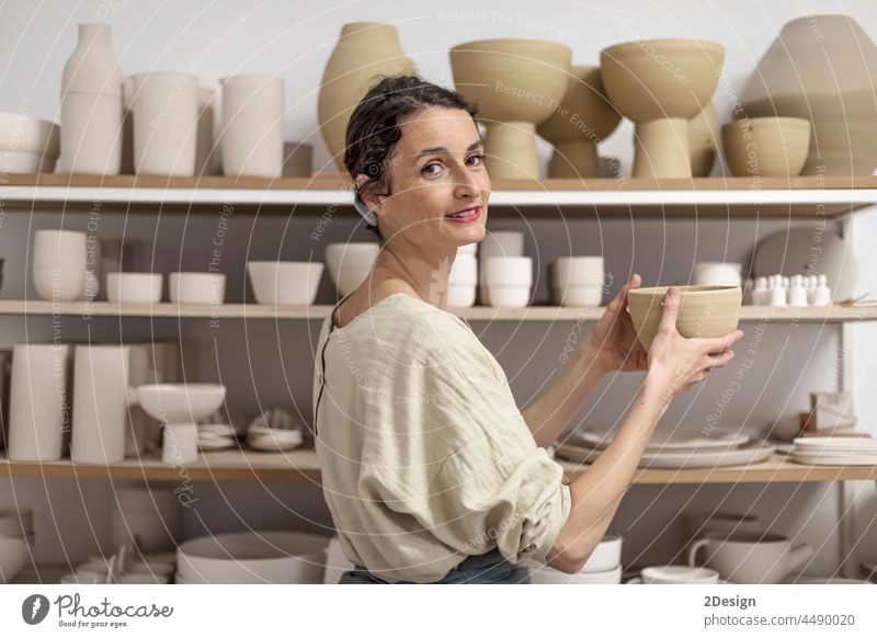 Junge Keramikerin im Haus mit handgefertigtem Tonprodukt. Konzeption der Töpferei Handwerk Frau Kunstgewerbler Beteiligung Lächeln in die Kamera schauen