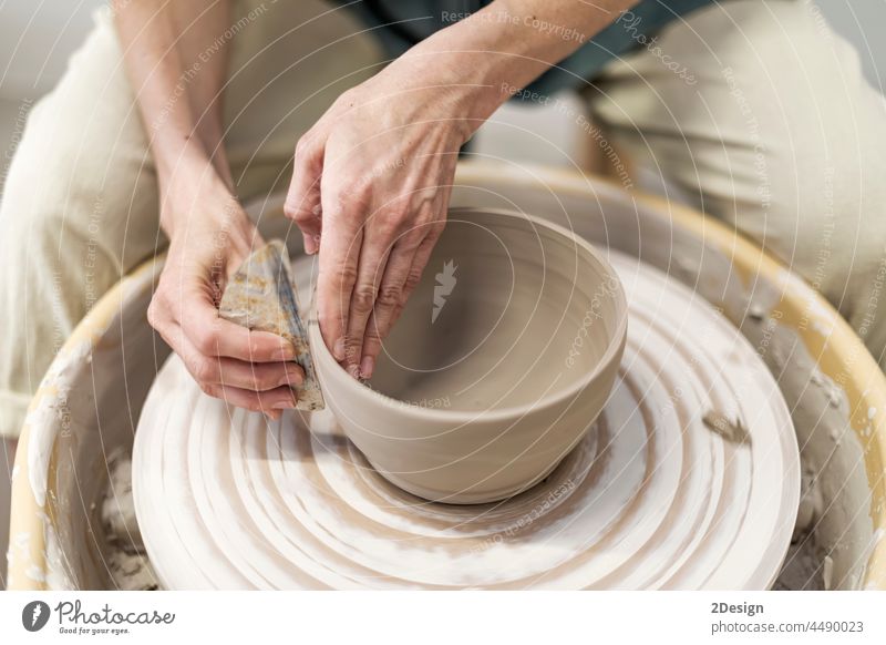 Die Hände einer jungen Frau arbeiten an einer Töpferscheibe in einer gemütlichen Werkstatt und stellen eine Vase oder einen Becher her Ton Hand Rad Nahaufnahme