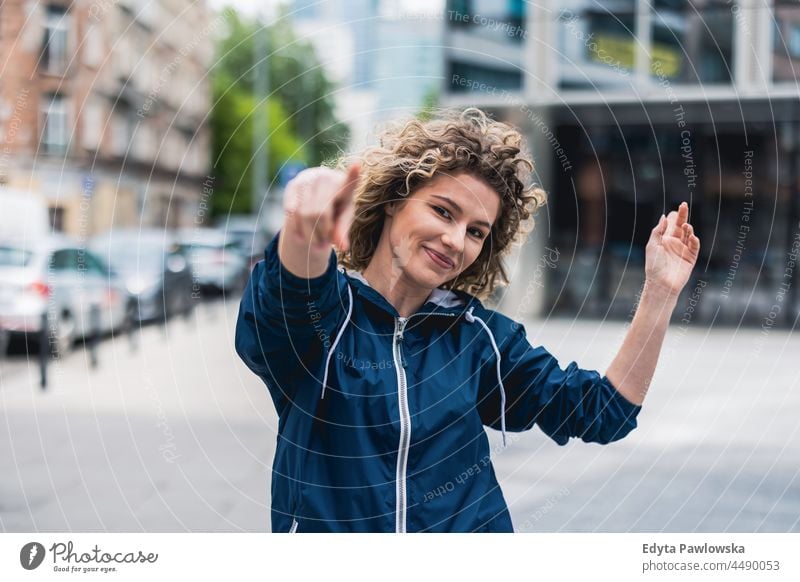 Junge Frau tanzt in den Straßen der Stadt Warschau Tag Spaß Kräusel Frisur Sommer Fröhlichkeit im Freien Tourist Schönheit Lächeln heiter echte Menschen