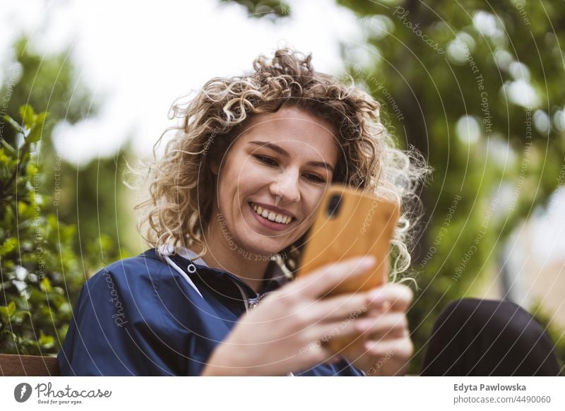 Junge Frau benutzt ein Mobiltelefon in der Stadt Warschau Tag Spaß Kräusel Frisur Sommer Fröhlichkeit im Freien Tourist Schönheit Lächeln heiter echte Menschen