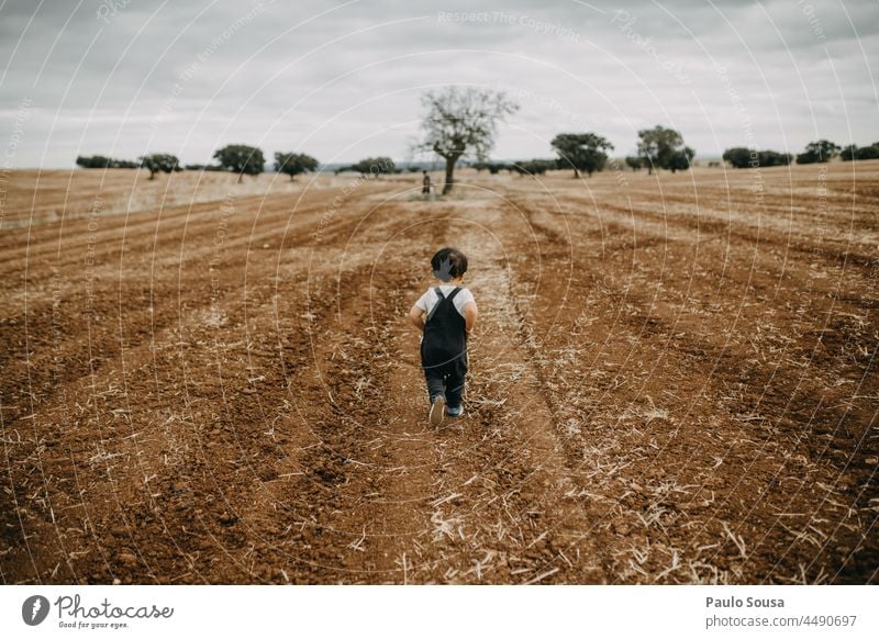 Rückansicht Kind läuft auf gepflügtem Feld 1-3 Jahre Kaukasier rennen Außenaufnahme Farbfoto Mensch Kindheit Freude Kleinkind Spielen Tag Fröhlichkeit Herbst