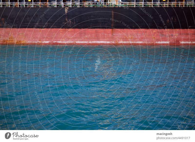 Schiffswand und Wasseröberfläche im Hafen schwarz rot blau Frachtschiff Anlegeplatz ankern Entladen Beladen Schifffahrt Logistik Warentransport Globalisierung