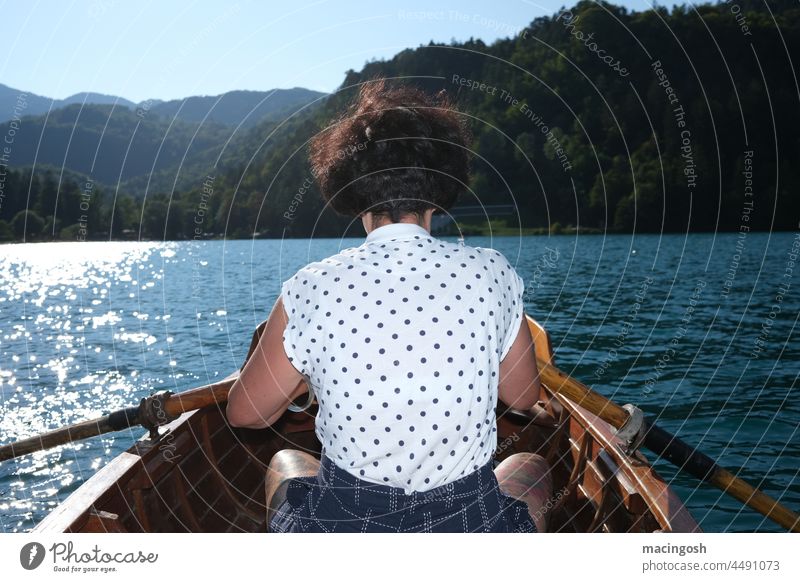 Rückansicht einer jungen Frau im Ruderboot Rudern Außenaufnahme See Wasser ruhig Ferien & Urlaub & Reisen Natur Ausflug Sommer Erholung Bootsfahrt