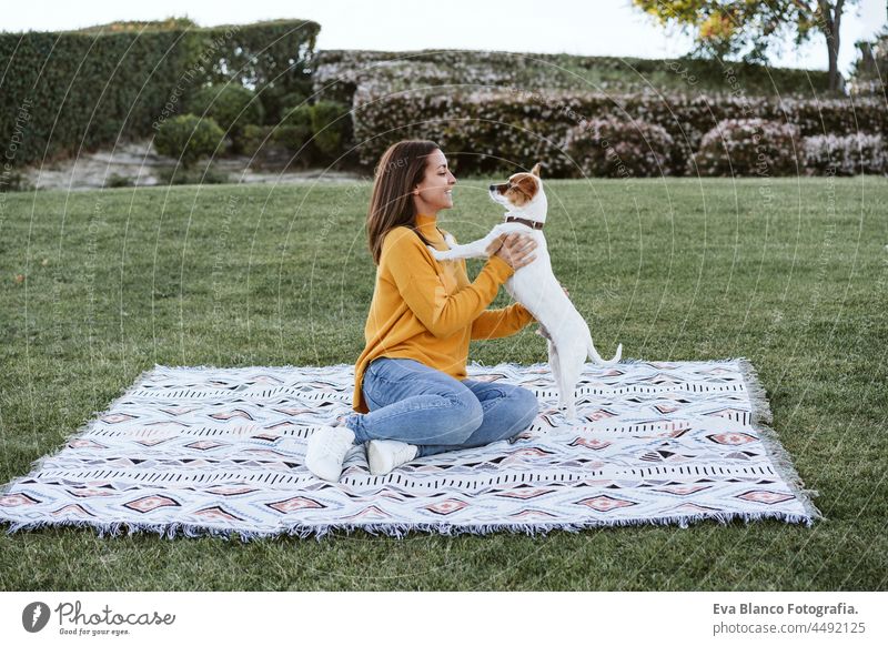 Frau, die Spaß mit Jack Russell Hund im Park, sitzen auf Decke im Herbst Saison. Haustiere und Liebe Konzept jack russell Glück Kuss genießen Plaid lutschen