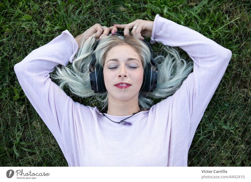 eine junge blonde Frau chillt und genießt Musik mit Kopfhörern Person Tanzen zuhören Model Erholung Lächeln Schüler stylisch trendy hübsch Kühlung Spaß