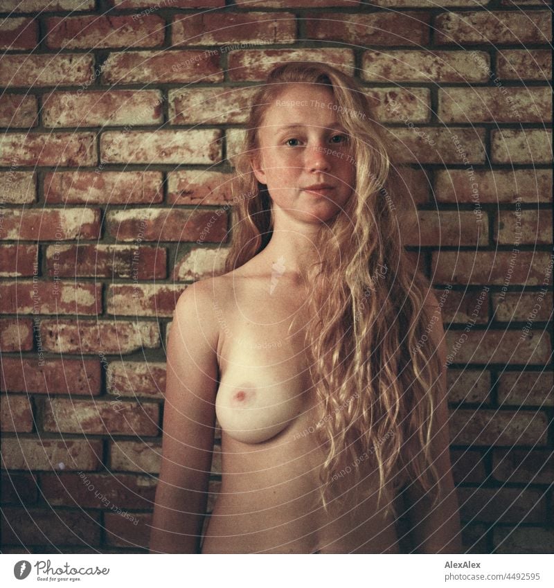 analoges Akt- Portrait einer jungen Frau mit Sommersprossen und roten Haaren, die vor einer Backsteinwand steht Porträt Ausstrahlung Ruhe kraftvoll hübsch