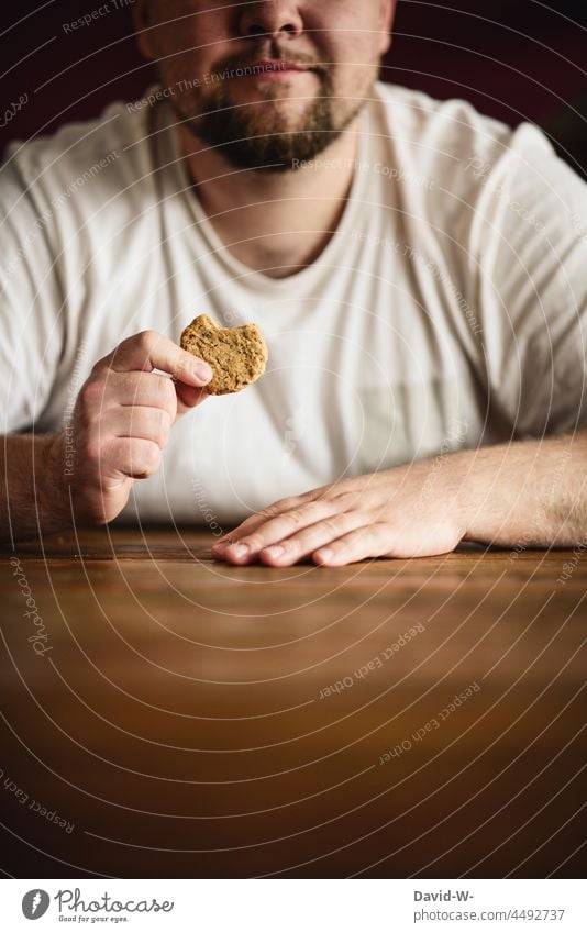 Mann isst einen Keks essen verfressen dick hungrig Übergewicht Appetit & Hunger Gewichtsprobleme zunehmen Kalorie Kalorienreich Zucker Lebensmittel ungesund