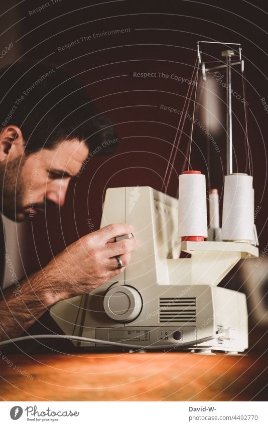 Mann bedient eine Nähmaschine bedienen nähen Hausmann konzentriert Schneidern Handwerk Beruf Freizeit & Hobby