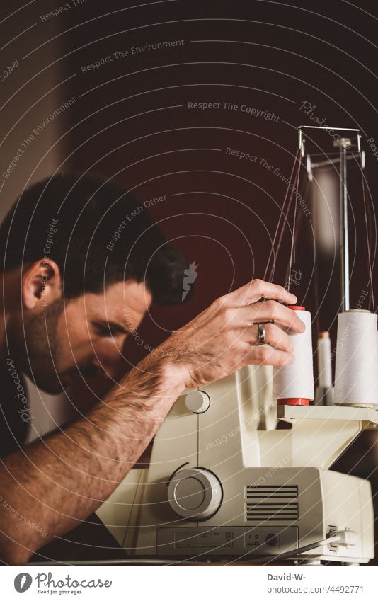 Mann arbeitet an einer Nähmaschine nähen Hausmann hobby Handwerk Handarbeit Schneider konzentriert arbeiten Faden Nähgarn
