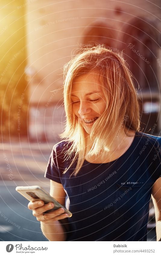 Frau mit Zahnspange benutzt Smartphone auf einer Straße in der Stadt Mobile laufen Lifestyle Kommunizieren online Porträt Telefon benutzend Fröhlichkeit tragbar