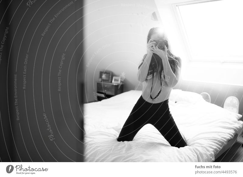 Junge Frau fotografiert auf einem Bett Kamera oben ohne langhaarig blitzlicht feminin Innenaufnahme Blick in die Kamera Porträt 18-30 Jahre Leggings Bettlaken