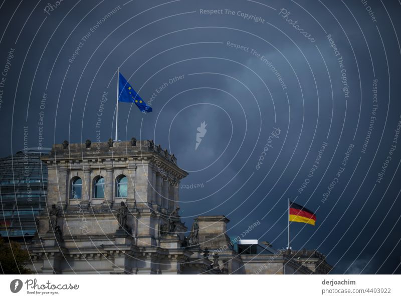 Ganz dunkle Wolken über dem Regierungsviertel. Zwei Fahnen, die Europa und die Deutsche wehen im stürmischen Wind über dem Bundestag. regierungsviertel