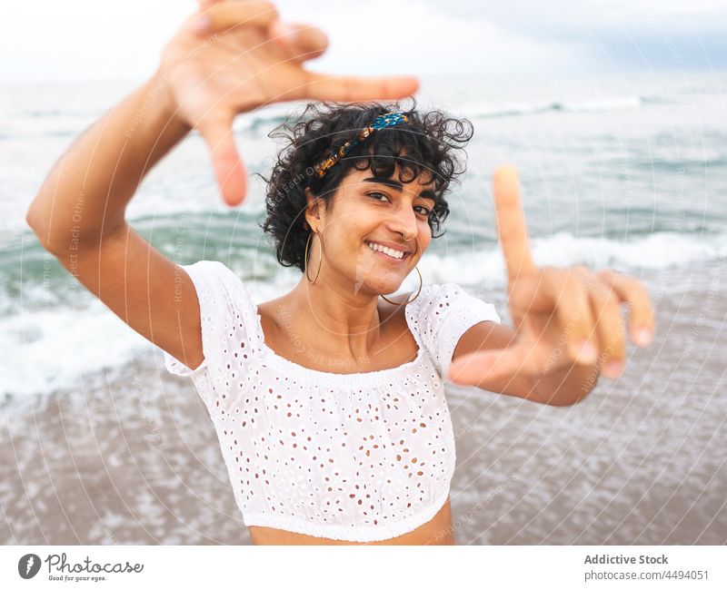 Ethnische Frau zeigt rahmende Geste am Meeresufer Rahmen gestikulieren Zeichen Foto MEER Sommer Lächeln Strand heiter ethnisch sorgenfrei Glück zeigen Seeküste