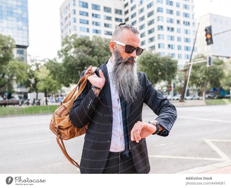 Stylischer Hipster, der die Zeit auf seiner Armbanduhr überprüft Mann Stil formal Straße Großstadt urban punktuell Tasche sich[Akk] beeilen Verkehr Licht modern