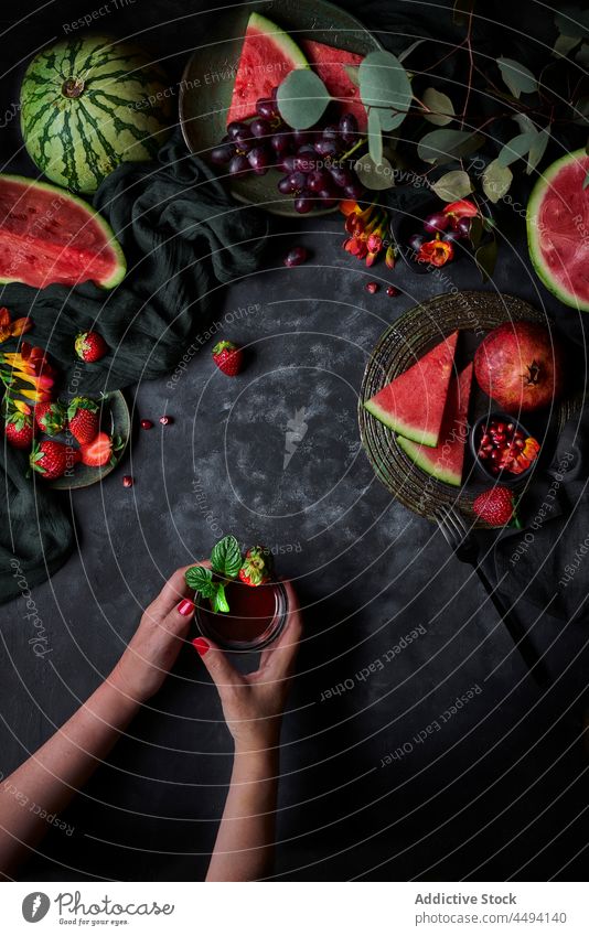 Unbekannte Frau mit Erfrischungsgetränk auf Tisch mit Wassermelone trinken Getränk Basilikum Erdbeeren Vitamin gesunde Ernährung Granatapfel Traube organisch