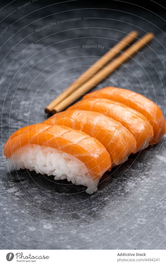 Leckere Sushi mit frischem Lachs Japanisch Tradition Küche hölzern Essstäbchen Reis Meeresfrüchte Mahlzeit Fisch Lebensmittel dienen Kulisse Asiatische Küche