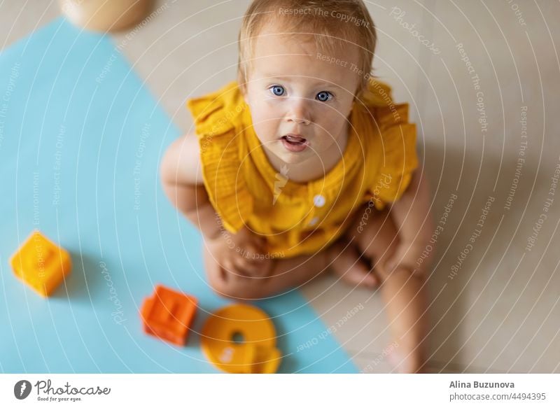 kleine kaukasische Baby-Mädchen zehn Monate alt spielen mit pädagogischen Silizium Spielzeug zu Hause oder Kinderzimmer. Kind hat Spaß mit bunten Spielsachen auf weißem Hintergrund