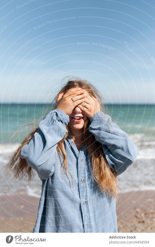 Frau bedeckt Gesicht mit Händen Sommer Sonnenlicht Küstenlinie Meeresufer Hand trendy tagsüber Wind Tierhaut friedlich Vorschein Zeitgenosse gestikulieren