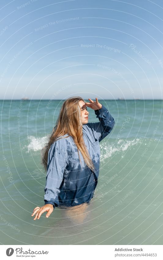 Frau im nassen Hemd im Meer stehend Wasser MEER Natur Entfernung beobachten erkunden warten Sommer Glück friedlich Sonnenlicht genießen charmant jung Windstille