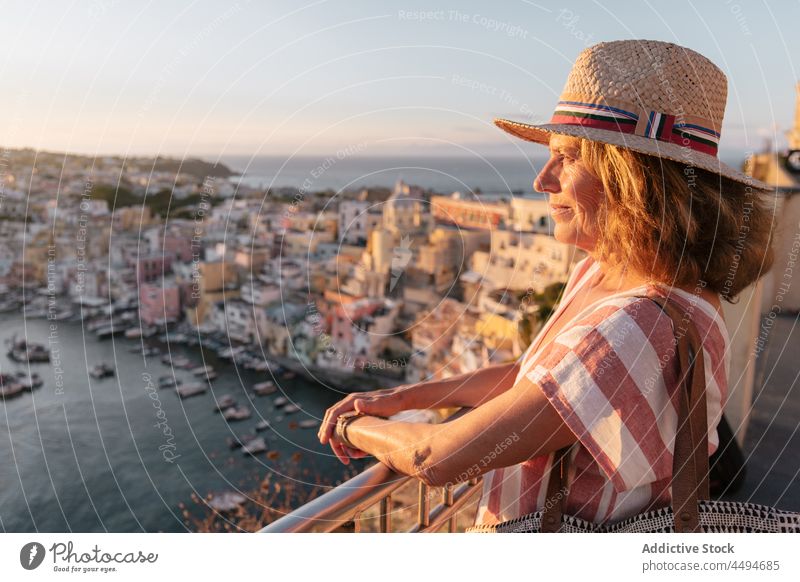 Glückliche weibliche Reisende bewundert Küstenstadt und Meer bei Sonnenuntergang Frau bewundern MEER Stadt Insel Tourist Urlaub friedlich malerisch Sommer Kleid