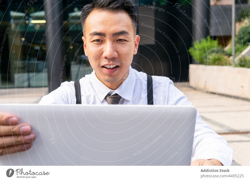 Stilvoller asiatischer Geschäftsmann arbeitet an einem Laptop in einem Stadtcafé Unternehmer Kaffee Internet online Mann Café benutzend Apparatur Gerät Gebäude